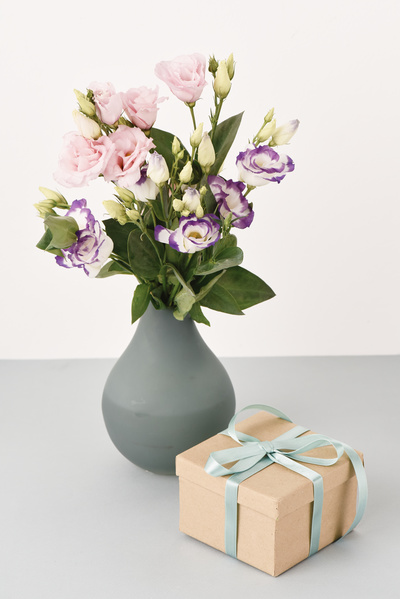 Vase of Flowers is Behind Gift with Blue Bow